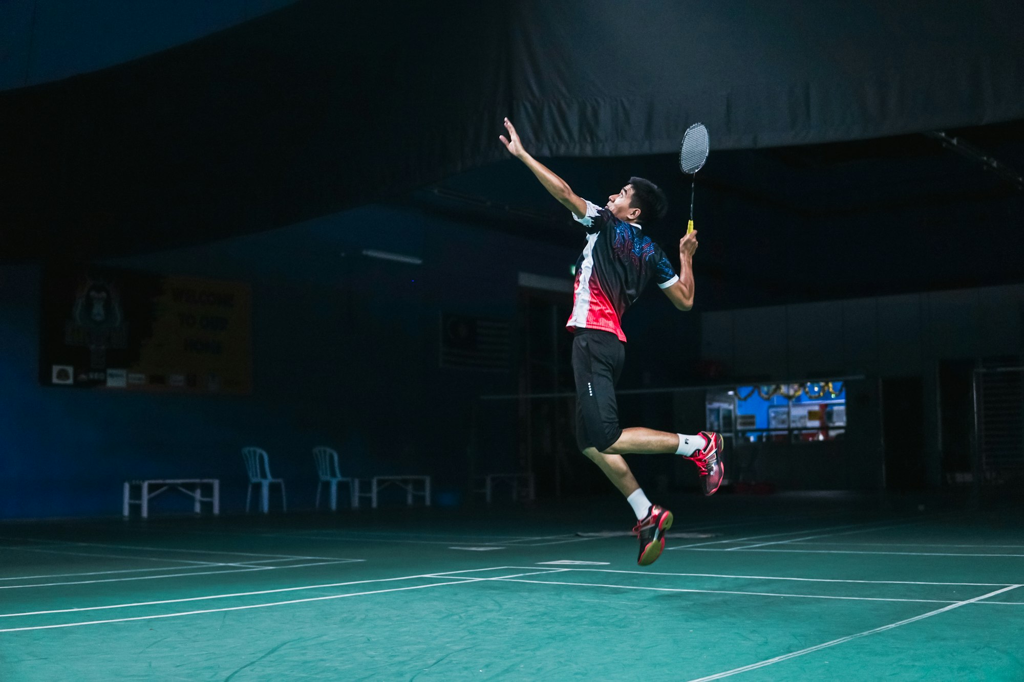 Badminton player mid-smash on an indoor court